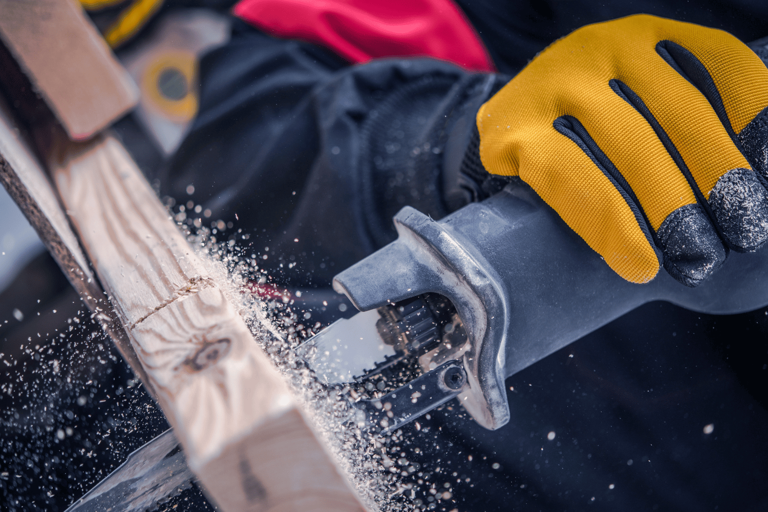 A person using a reciprocating saw to cut a piece of wood