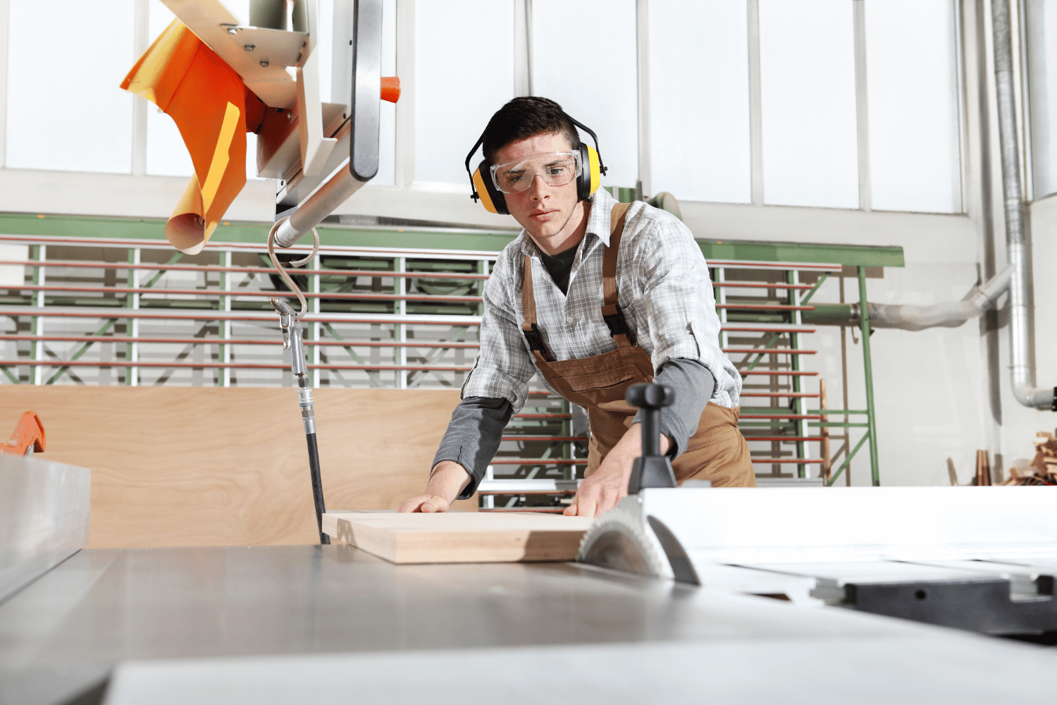 A person wearing safety glasses and ear protection while using a table saw
