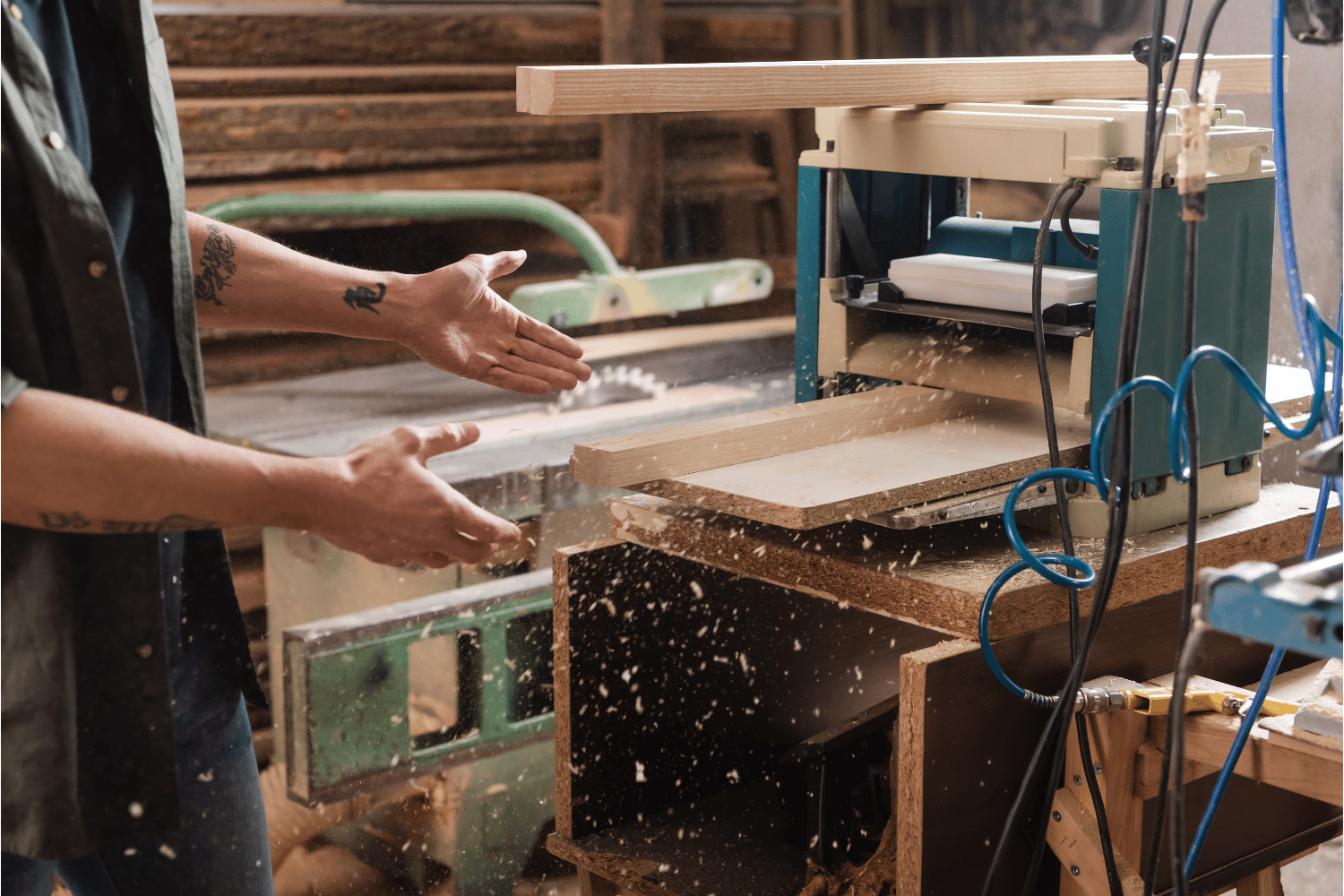A person using a thickness planer to plane multiple boards to the same thickness