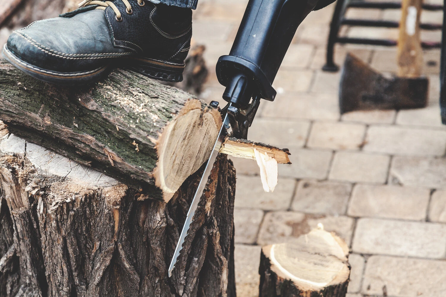 A person using a reciprocating saw to cut a tree branch
