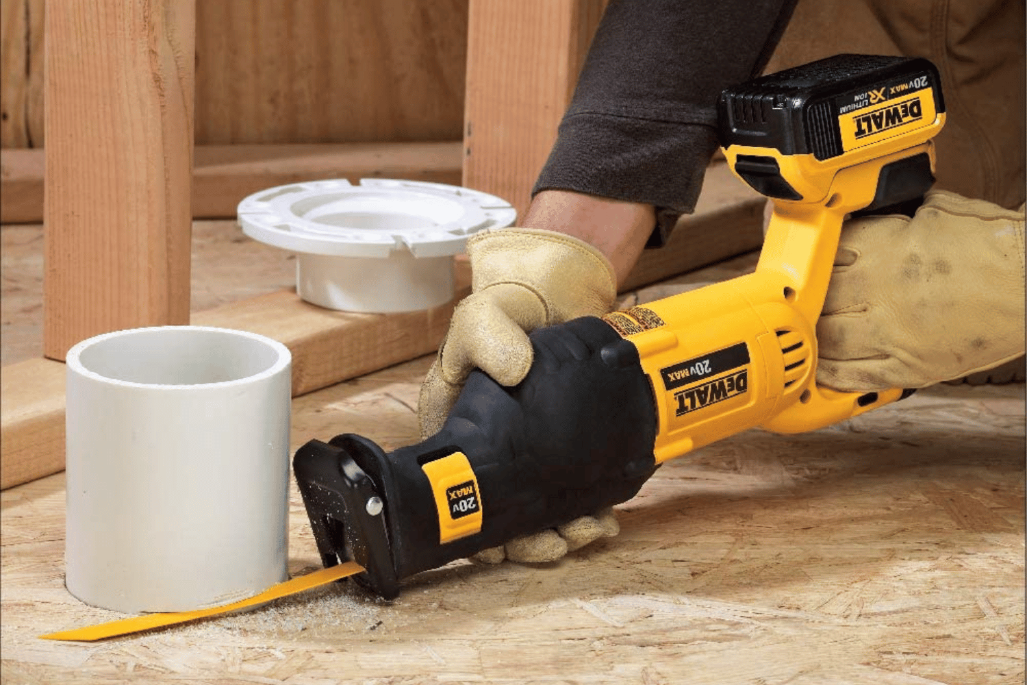 A person using a reciprocating saw with a scraper blade attachment to remove old plumbing lines