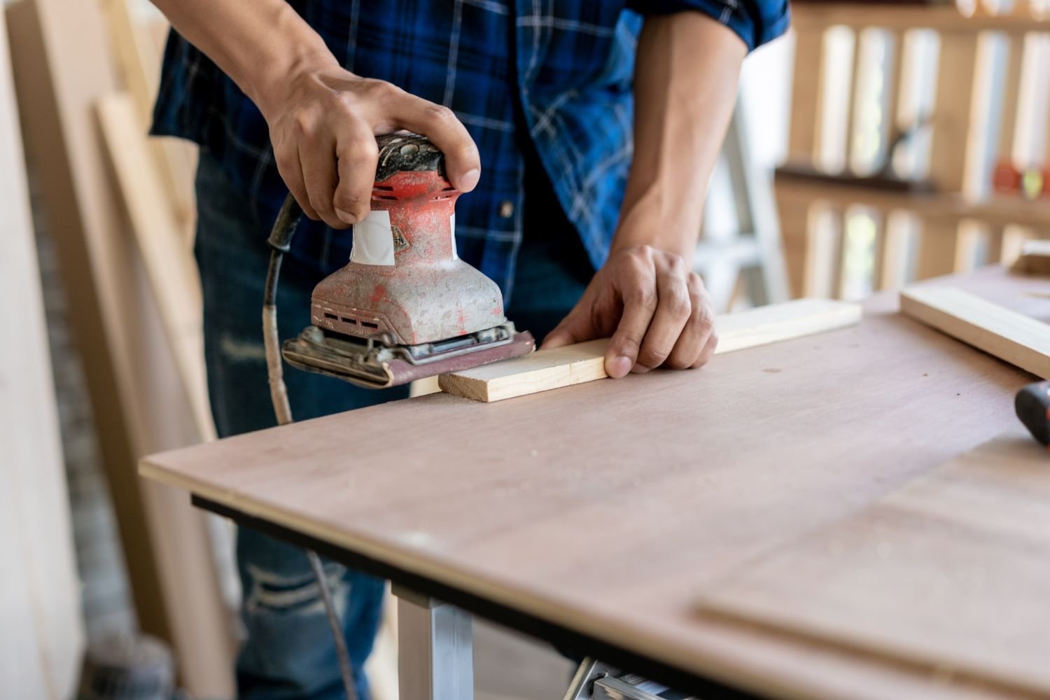 Sheet Pad Sander being used by a woodworker to smooth a piece of wood.
