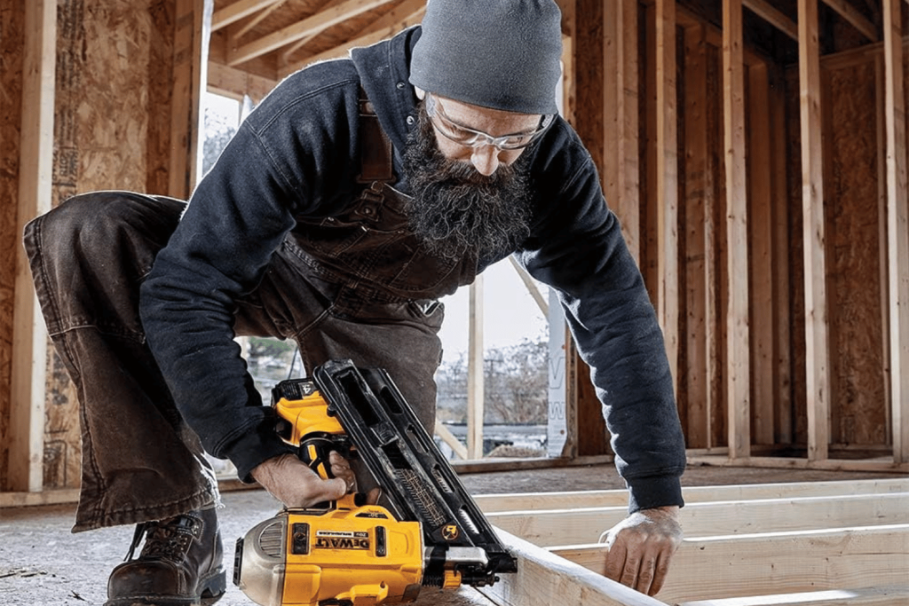 Using a cordless framing nailer to add a framing nail to wall frame
