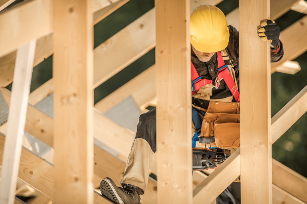 A construction worker using a framing nailer to frame a roof.